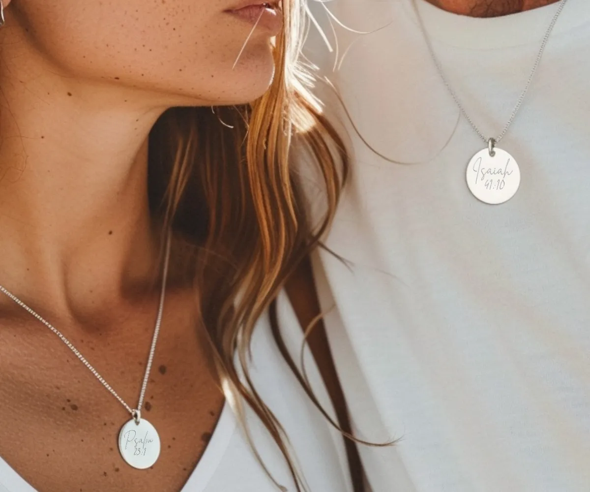 Couple wearing Bible verse pendants engraved with scripture references.